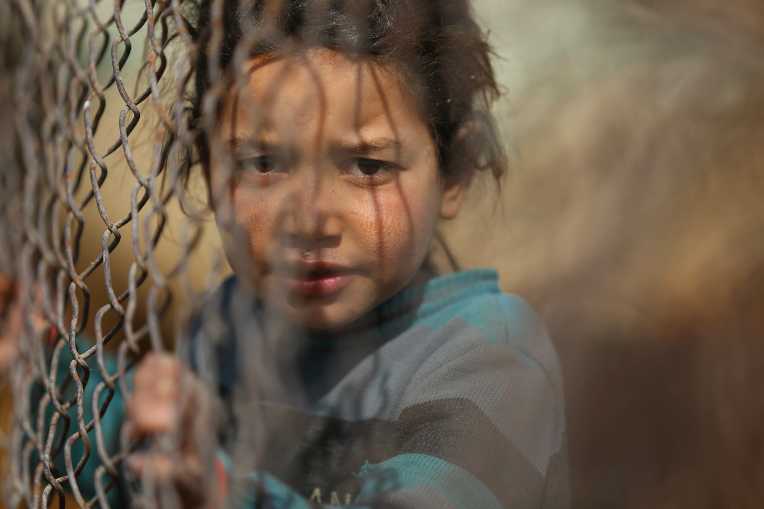 Criança atrás de vedação na Síria