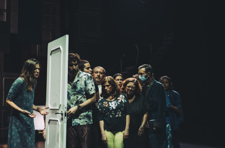 atores em palco atrás de um porta