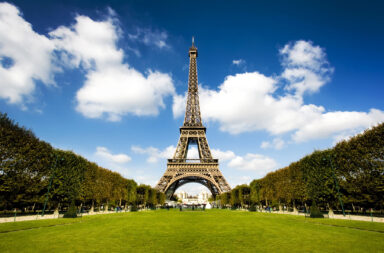 Torre Eiffel num dia de sol e céu azul, mas com nuvens