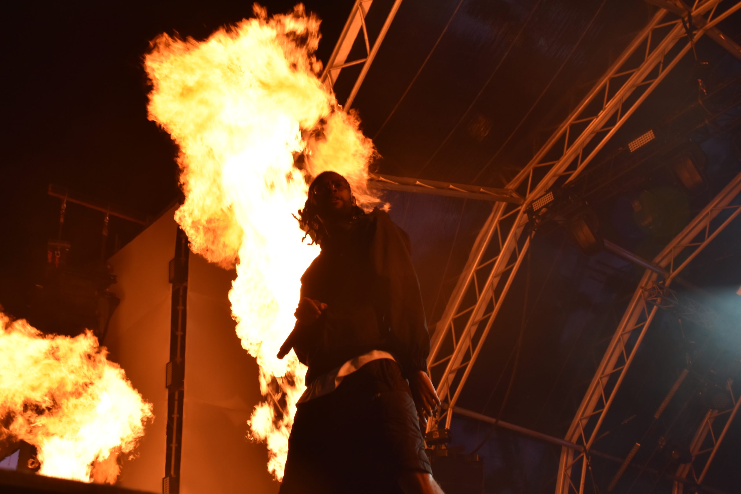 Cantor T-Rex em palco com projeção de fogo nas costas